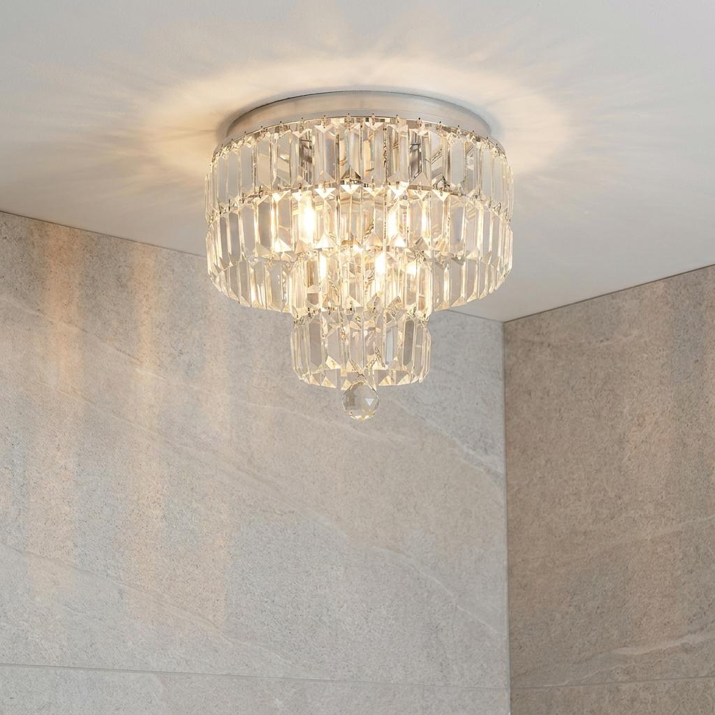 Tiered chrome and crystal flush ceiling light illuminating a modern room with stone-tiled walls.
