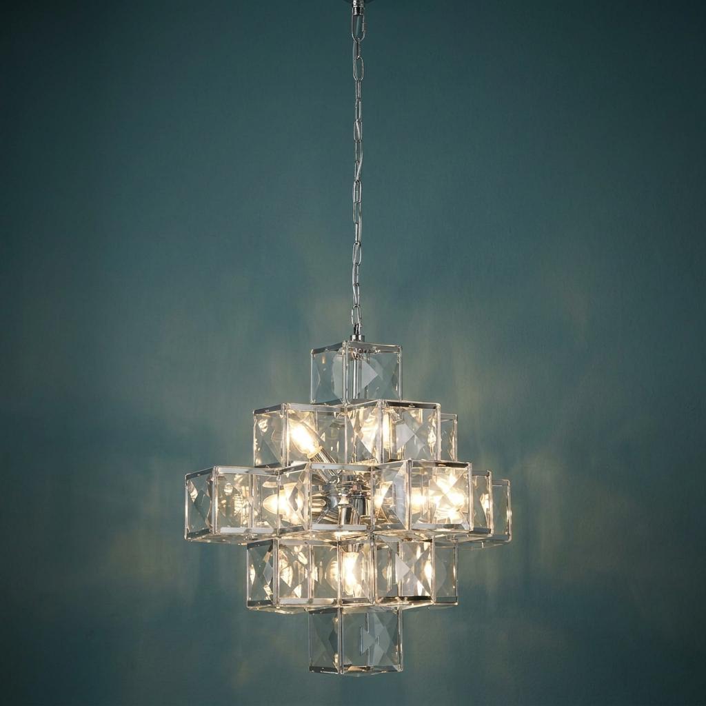Modern chrome and acrylic ceiling pendant with geometric cube design, lit against a teal wall.