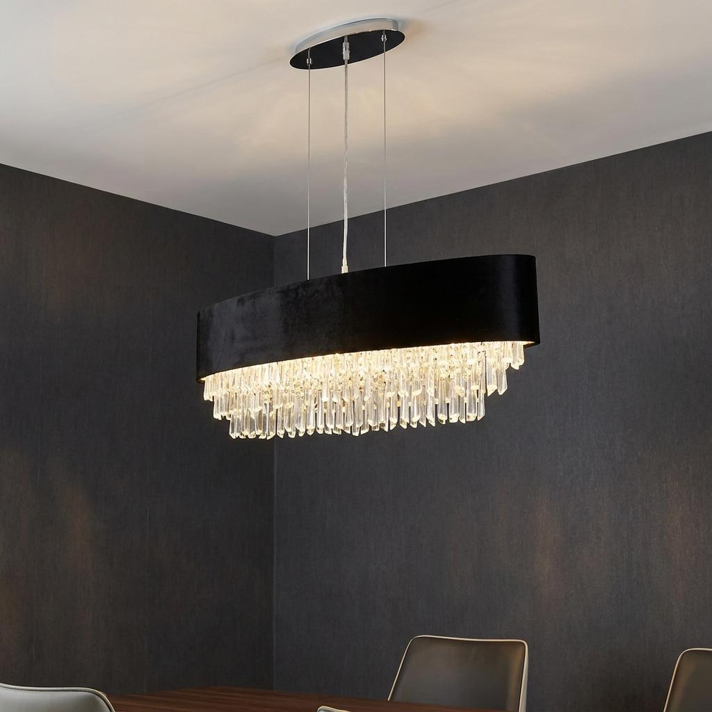 Oval black velvet pendant light with cascading crystal prisms hanging in a dining room with dark walls.