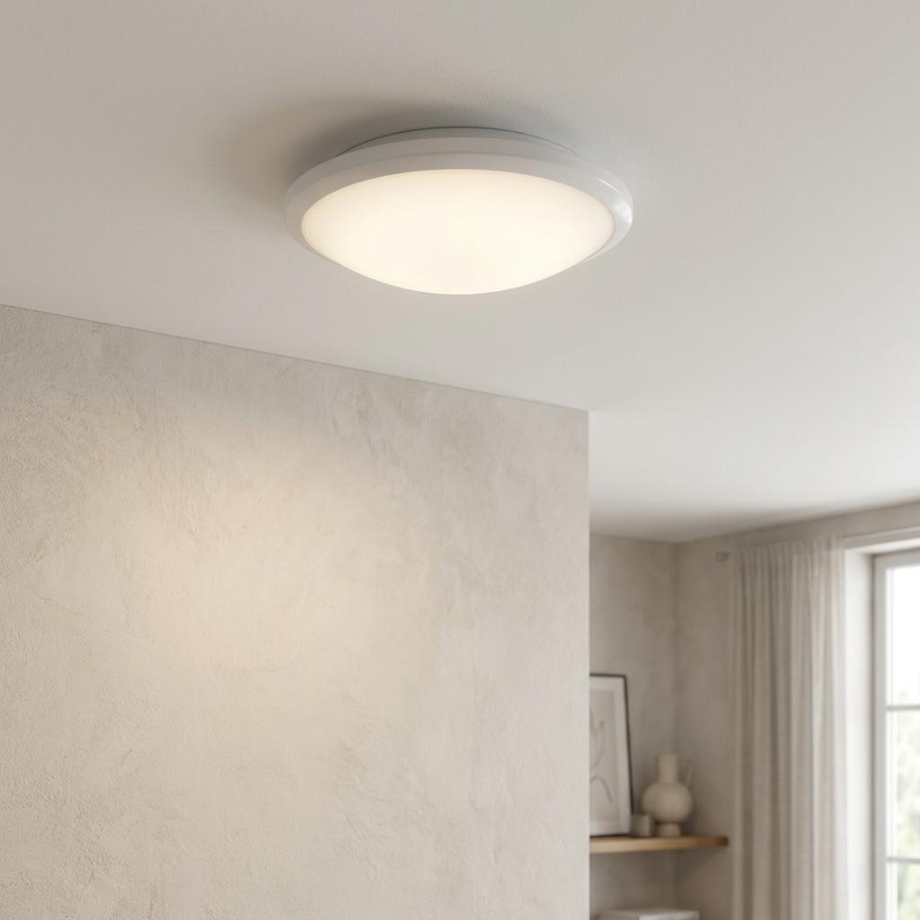 Circular white flush mount ceiling light with a frosted glass diffuser glowing in a modern neutral room.