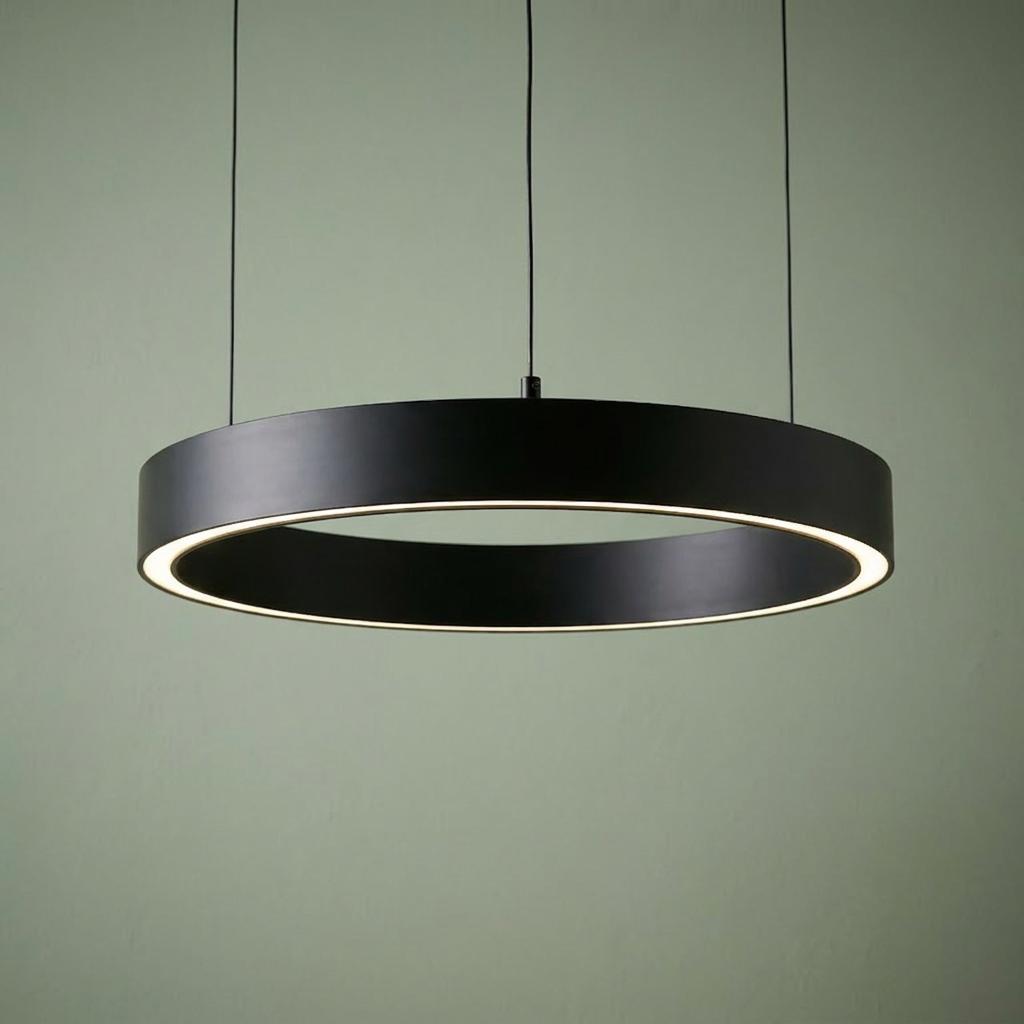 A black circular LED halo pendant light hanging against a soft green wall.