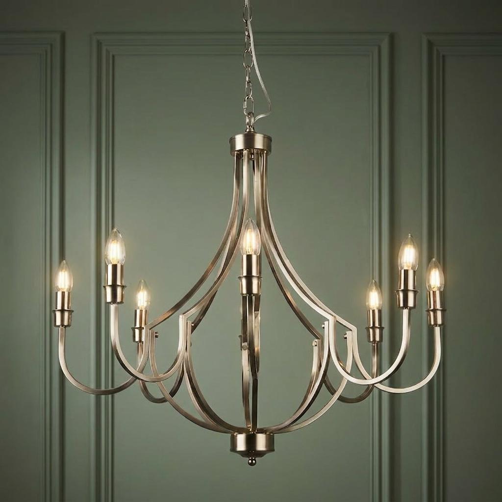 Elegant 8-light silver chandelier with curved metal arms and candle bulbs against a green paneled wall.