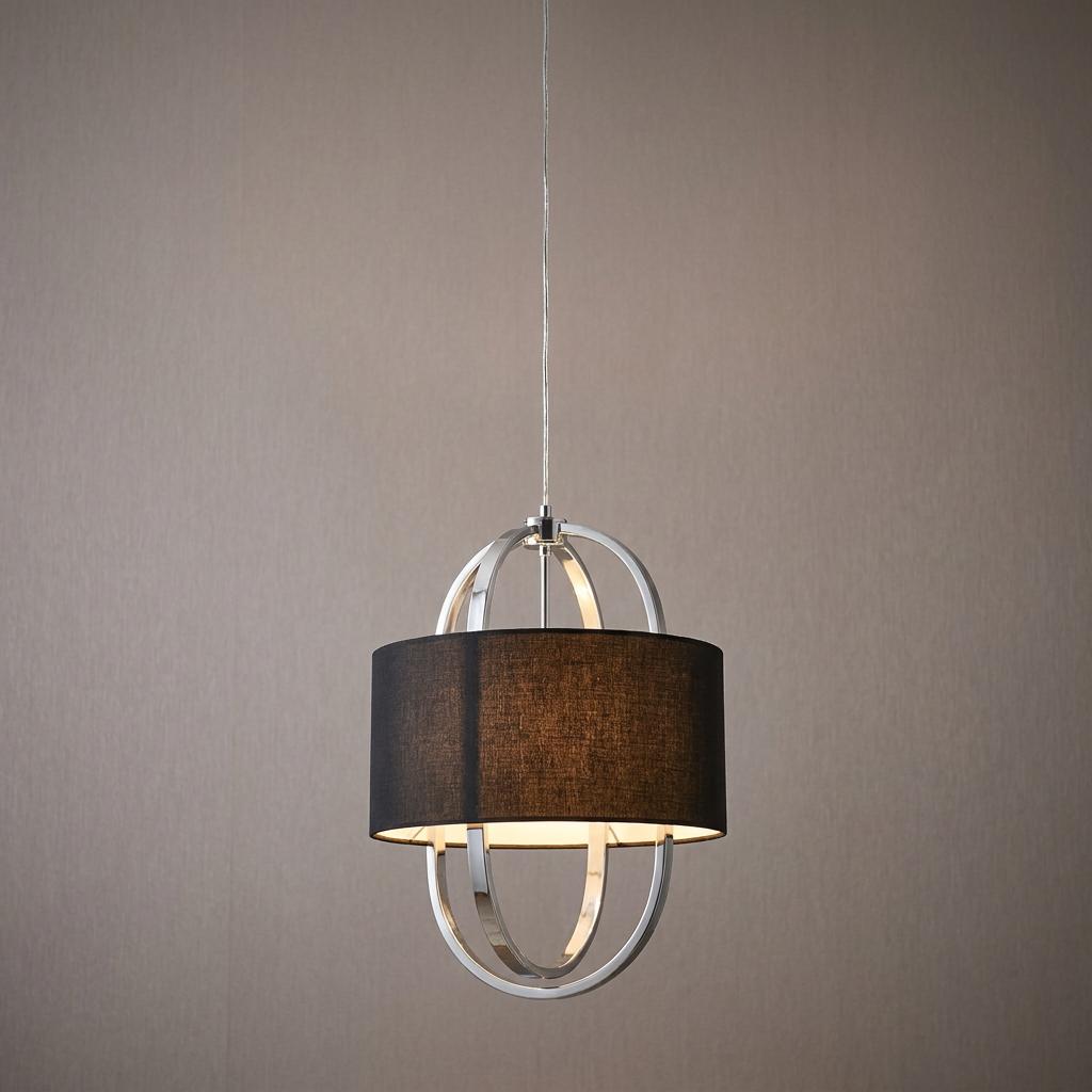 Chrome orbital pendant light with a black fabric drum shade, illuminated against a neutral wall.