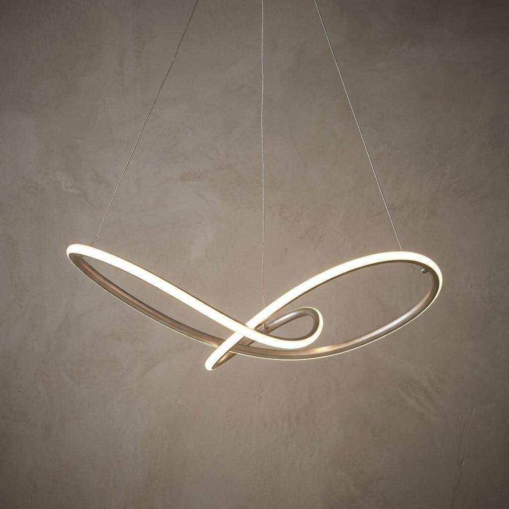 Modern silver LED pendant light in a twisted infinity loop design hanging against a textured neutral wall.