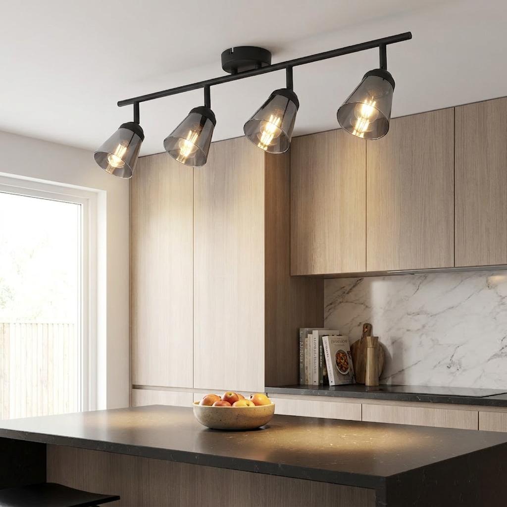 Modern black 4-light bar spotlight with smoked glass shades illuminating a kitchen island and wood cabinets.