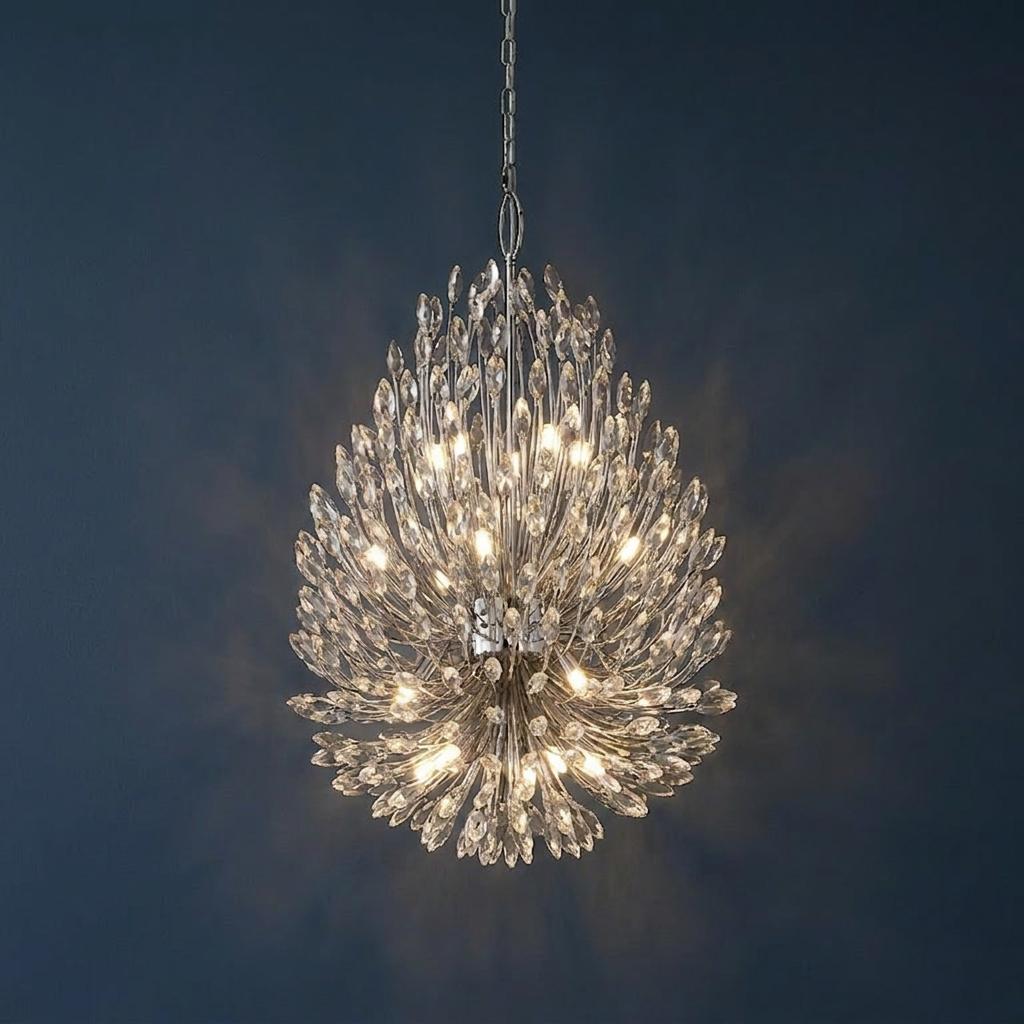 A pear-shaped chrome and crystal 20-light pendant chandelier glowing against a dark blue background.