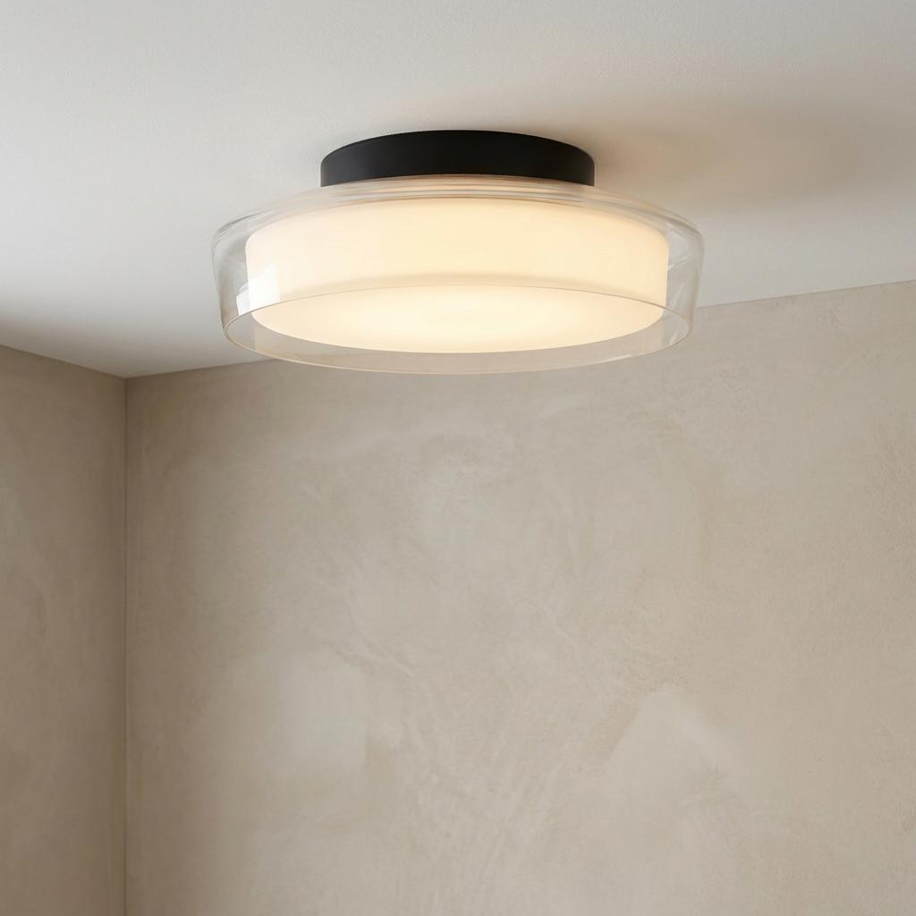 Black flush mount ceiling light with clear and opal glass shades illuminated on a neutral ceiling.
