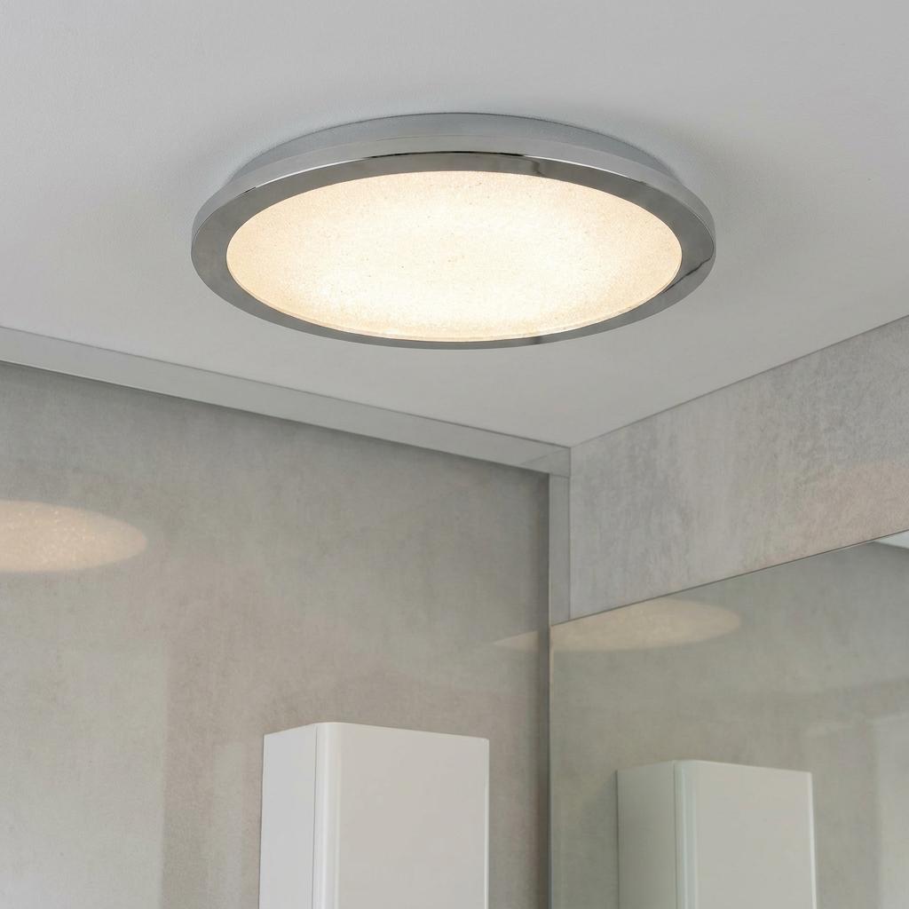 Round LED flush ceiling light with a polished chrome trim and a crystal sand diffuser in a bathroom.