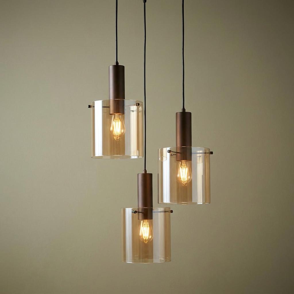 Three-light multi-drop pendant featuring staggered amber glass cylindrical shades and brown metal fixtures.