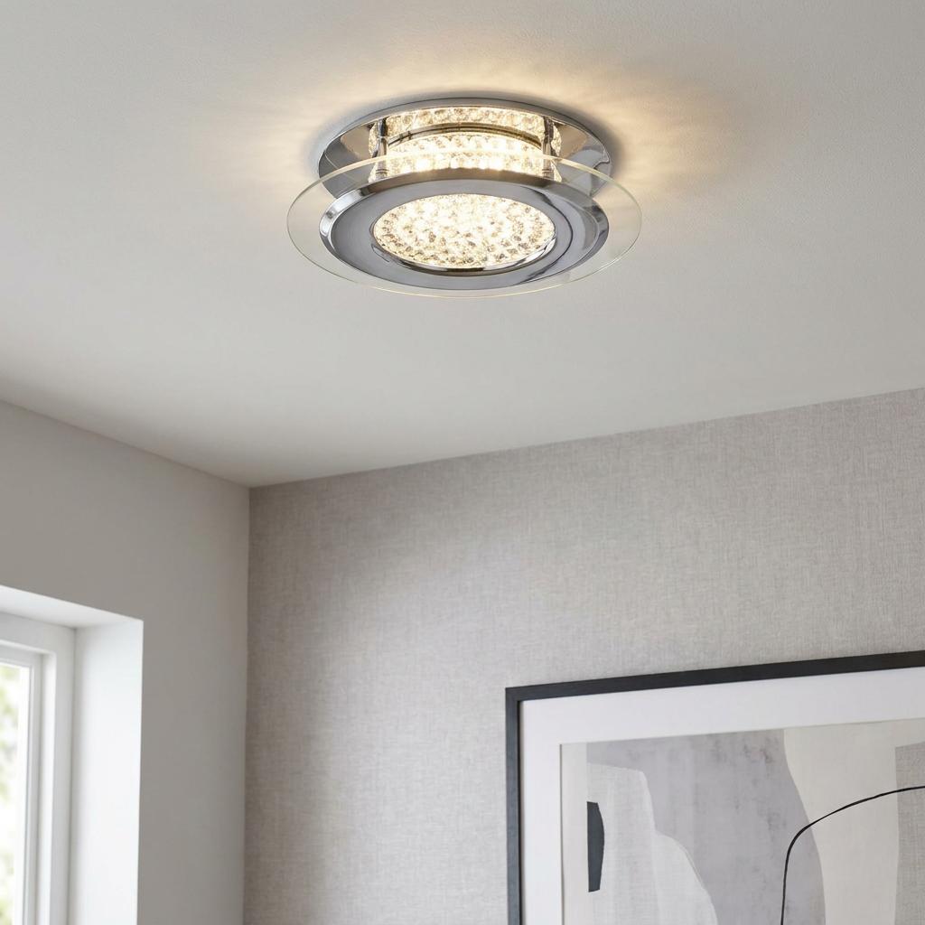 Modern chrome and crystal LED flush ceiling light with a clear glass ring glowing in a contemporary room.