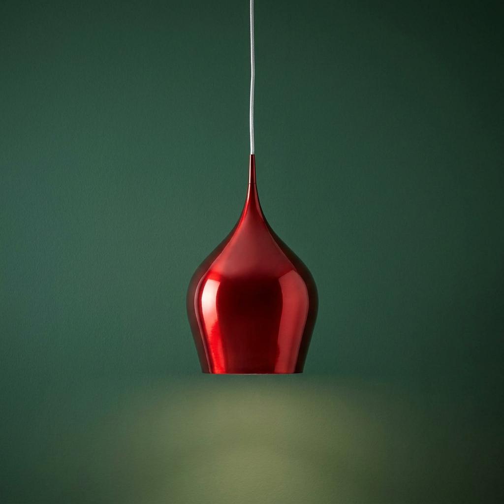 A metallic red teardrop pendant light hanging against a dark green background, casting a warm glow downwards.