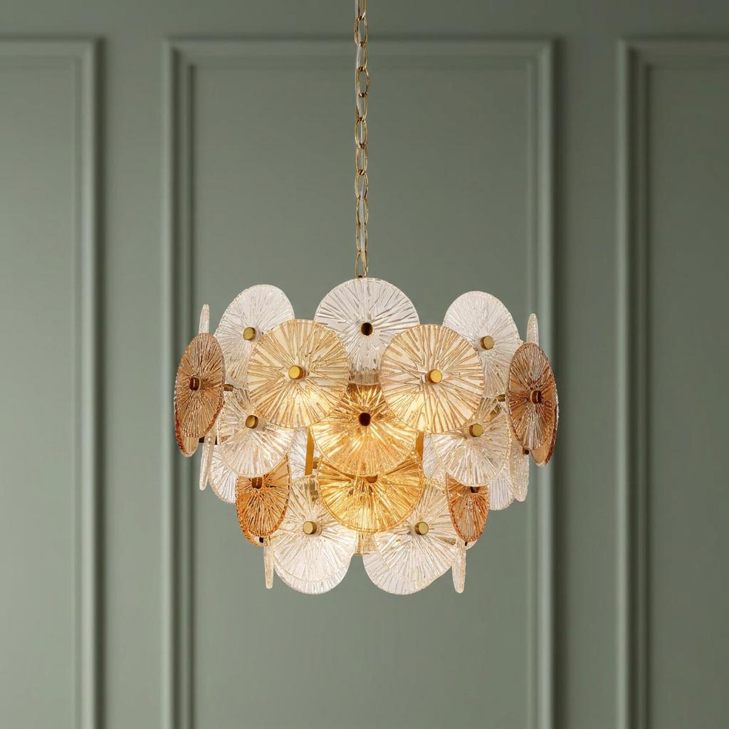 Chandelier featuring textured amber and clear glass discs hanging against a sage green paneled wall.