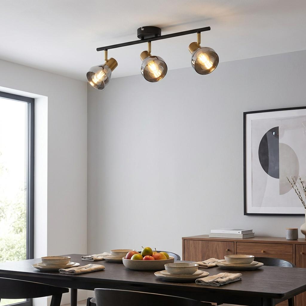 Three-light black and brass ceiling spotlight with smoked glass shades in a modern dining room.