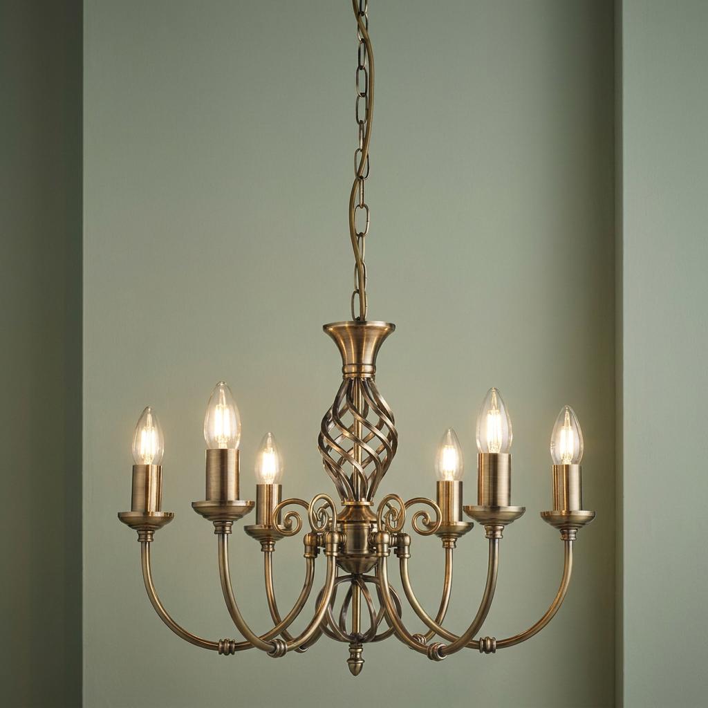 A six-light brass chandelier with candle-style bulbs and a twisted cage center against a muted green wall.