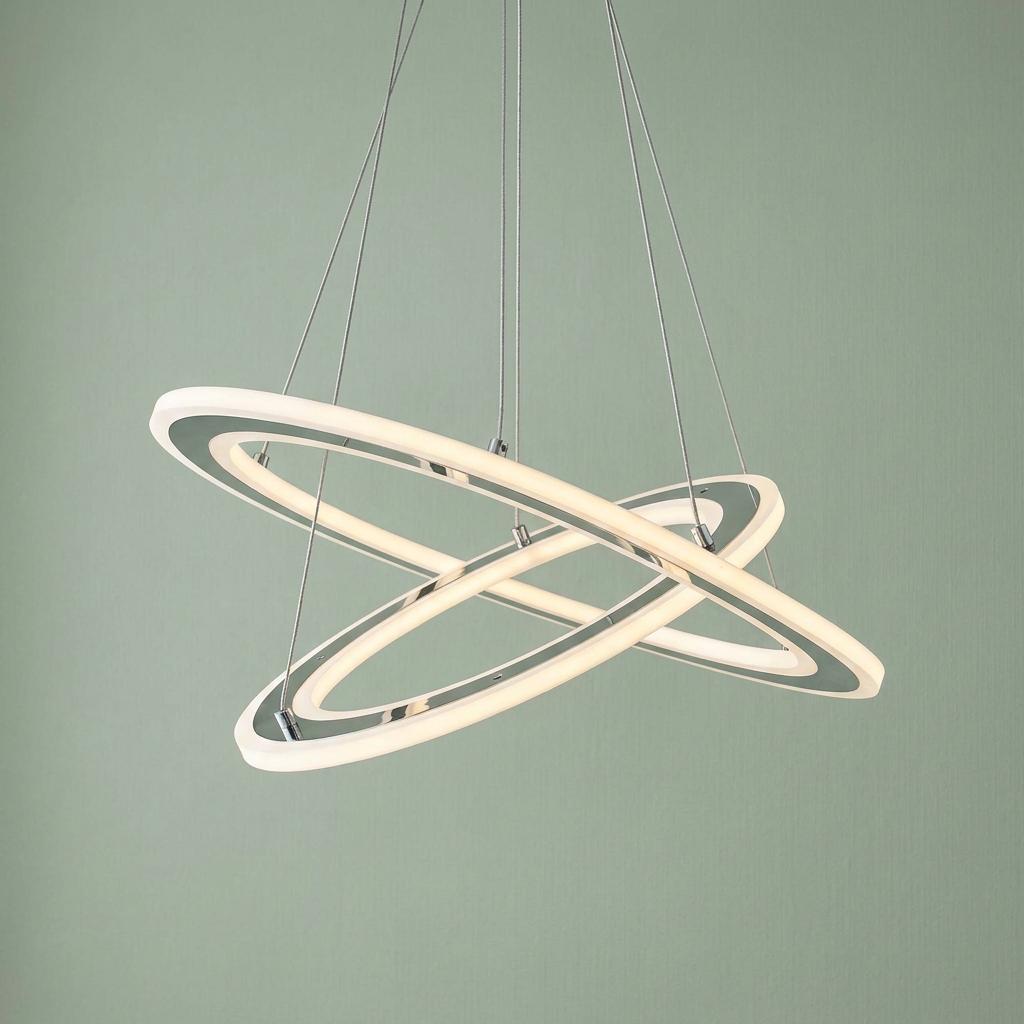 Interlocking chrome and frosted acrylic LED hoop pendant light suspended by wires against a light green background.
