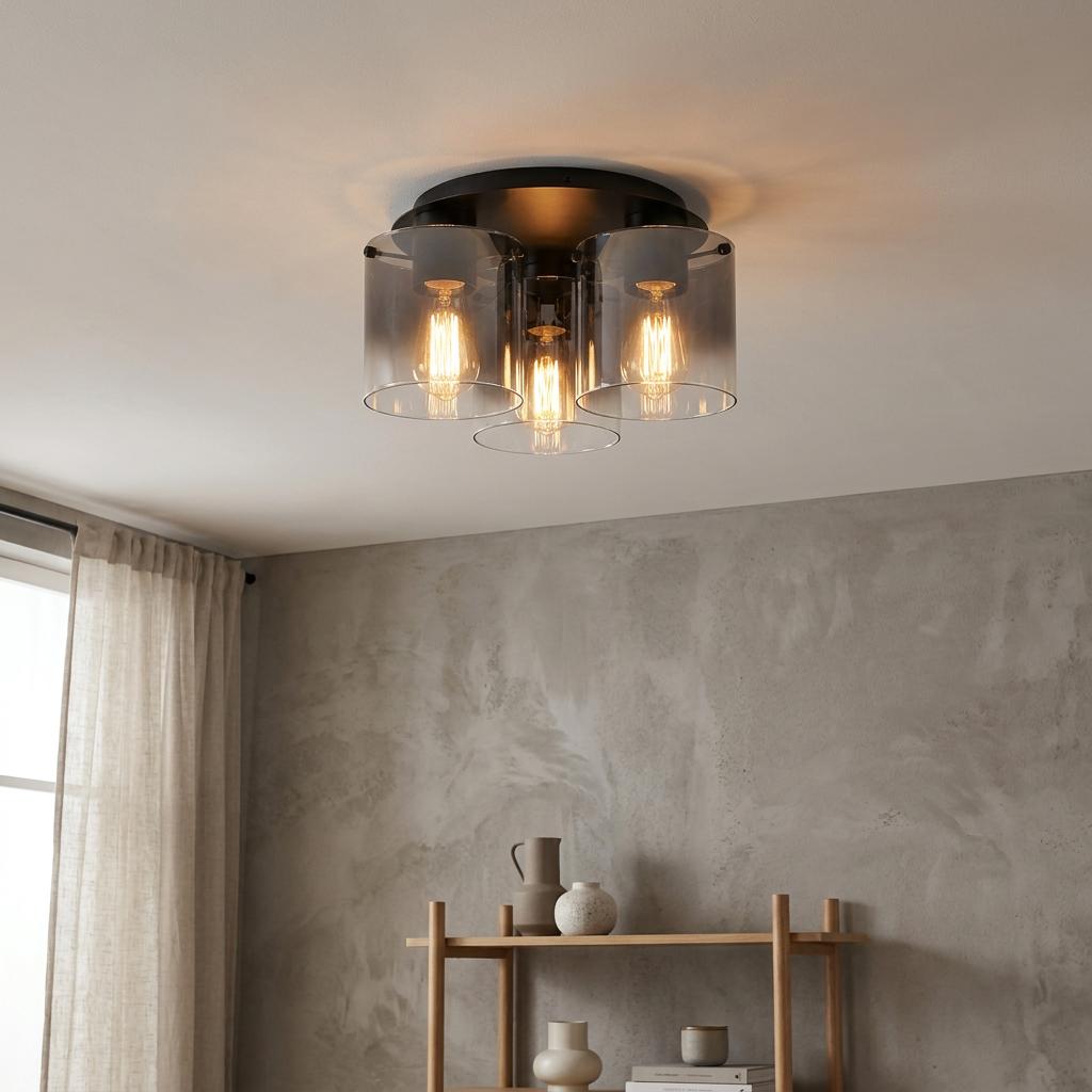 Matt black flush ceiling light with three smoked glass cylinder shades and warm glowing bulbs in a modern room.