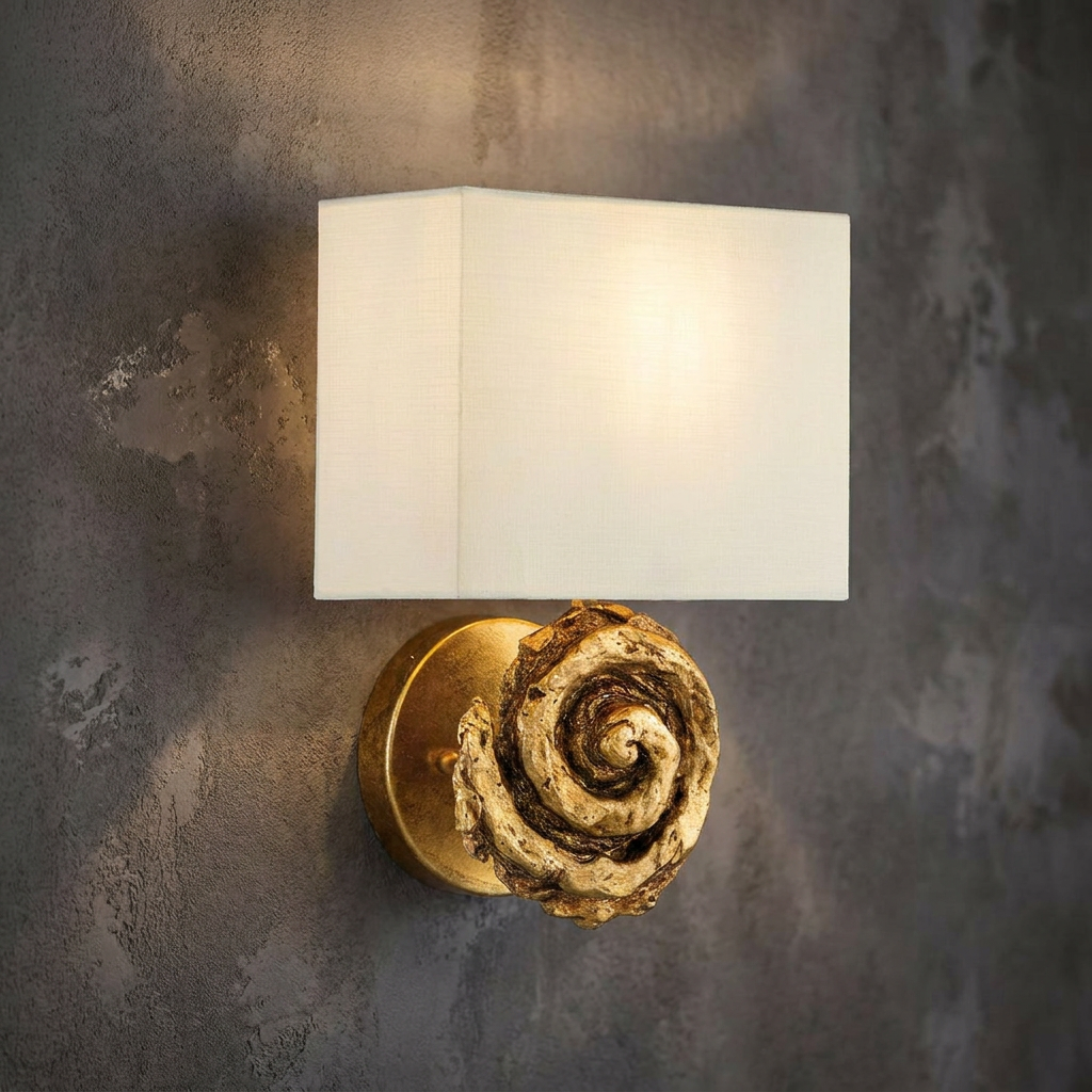 Swirl wall light in gold leaf finish with a white fabric rectangular shade against a grey textured wall.