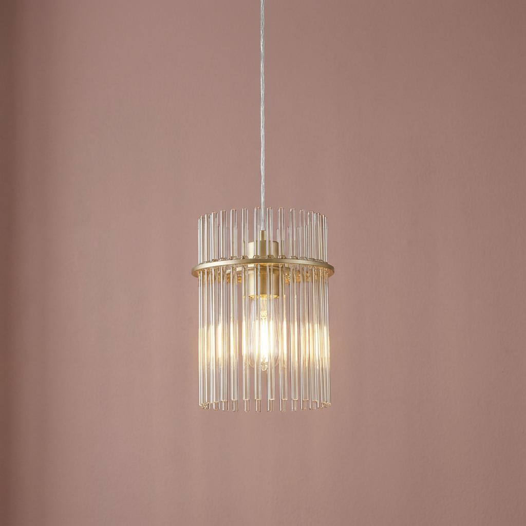 Modern pendant light featuring a gold ring and vertical champagne glass rods against a mauve background.