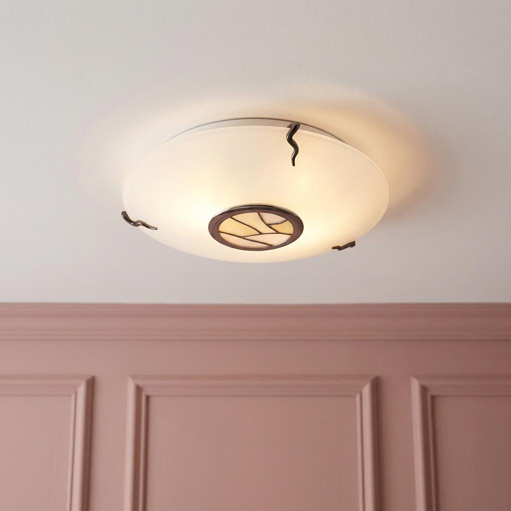 Tiffany flush mount beige and white glass ceiling light with bronze accents above a pink paneled wall.