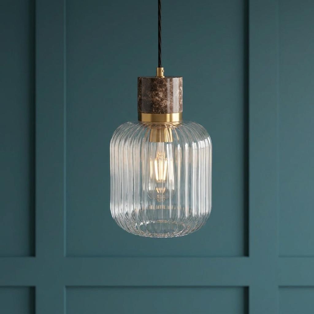 Travi Emperador marble and brass pendant light with a ribbed glass shade against a dark teal paneled wall.