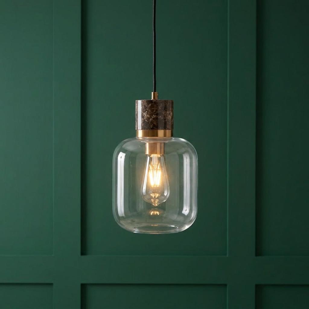Travi Emperador marble and brass pendant light with a clear glass shade against a dark green paneled wall.