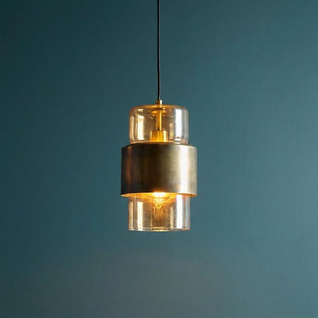 Modern brass patina pendant light with champagne glass cylinders hanging against a dark teal wall.