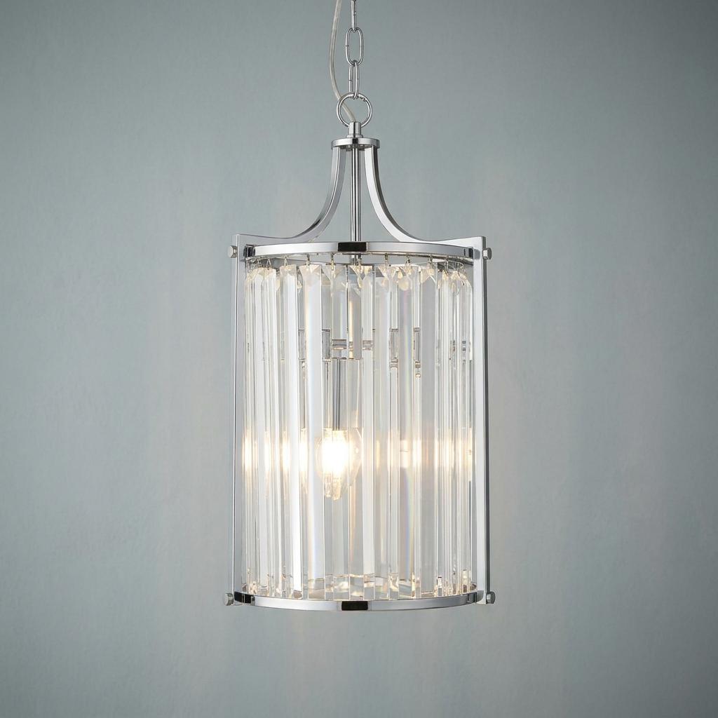 Cylindrical chrome pendant light with vertical crystal glass prisms and a lit bulb against a neutral wall.