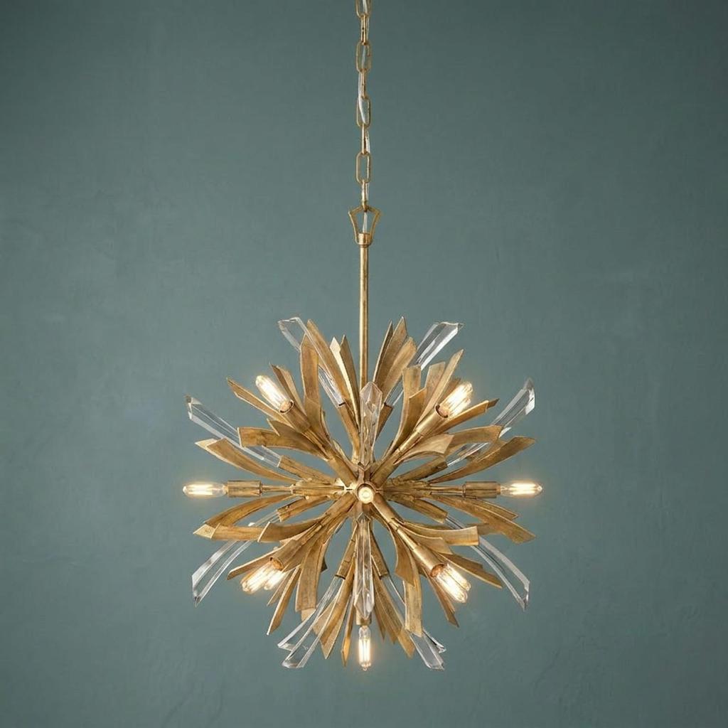Gold starburst chandelier with crystal accents and thirteen glowing lights against a dark textured wall.