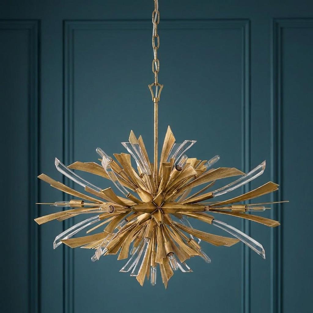 A starburst-style Vida 13-light gold pendant chandelier with crystal accents against a teal paneled wall.
