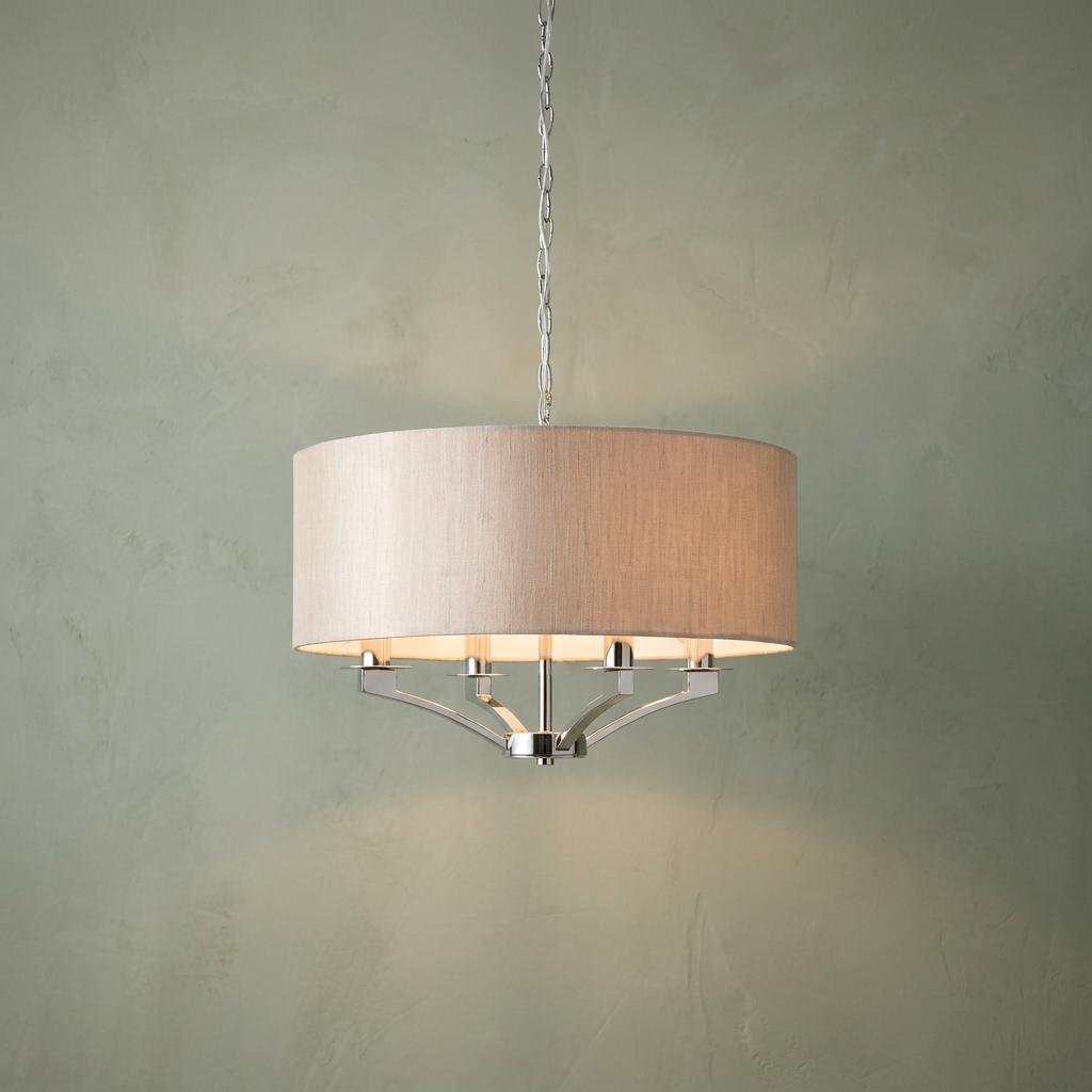 Polished nickel 4-light pendant with a beige fabric drum shade, suspended by a chain against a sage green wall.