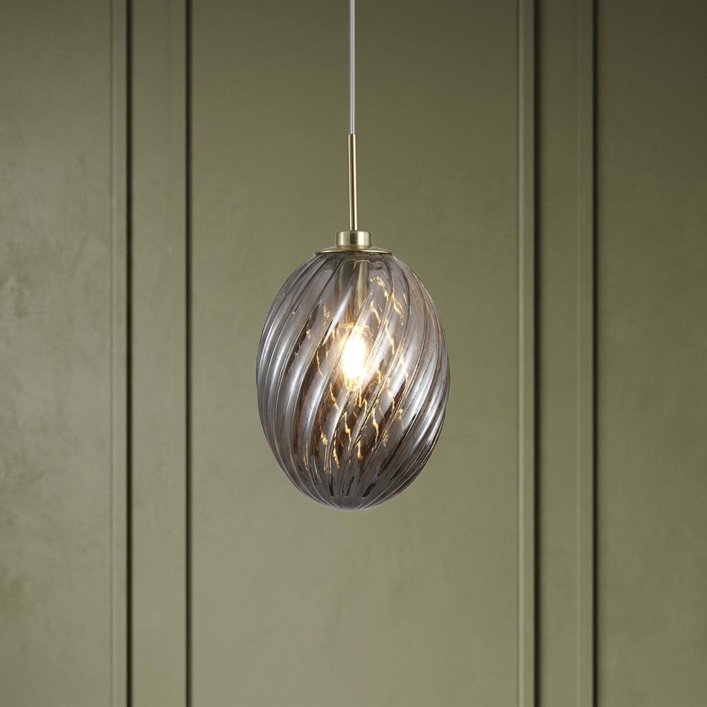 Satin brass pendant light with a smoked, swirled glass oval shade, hanging against a sage green wall.