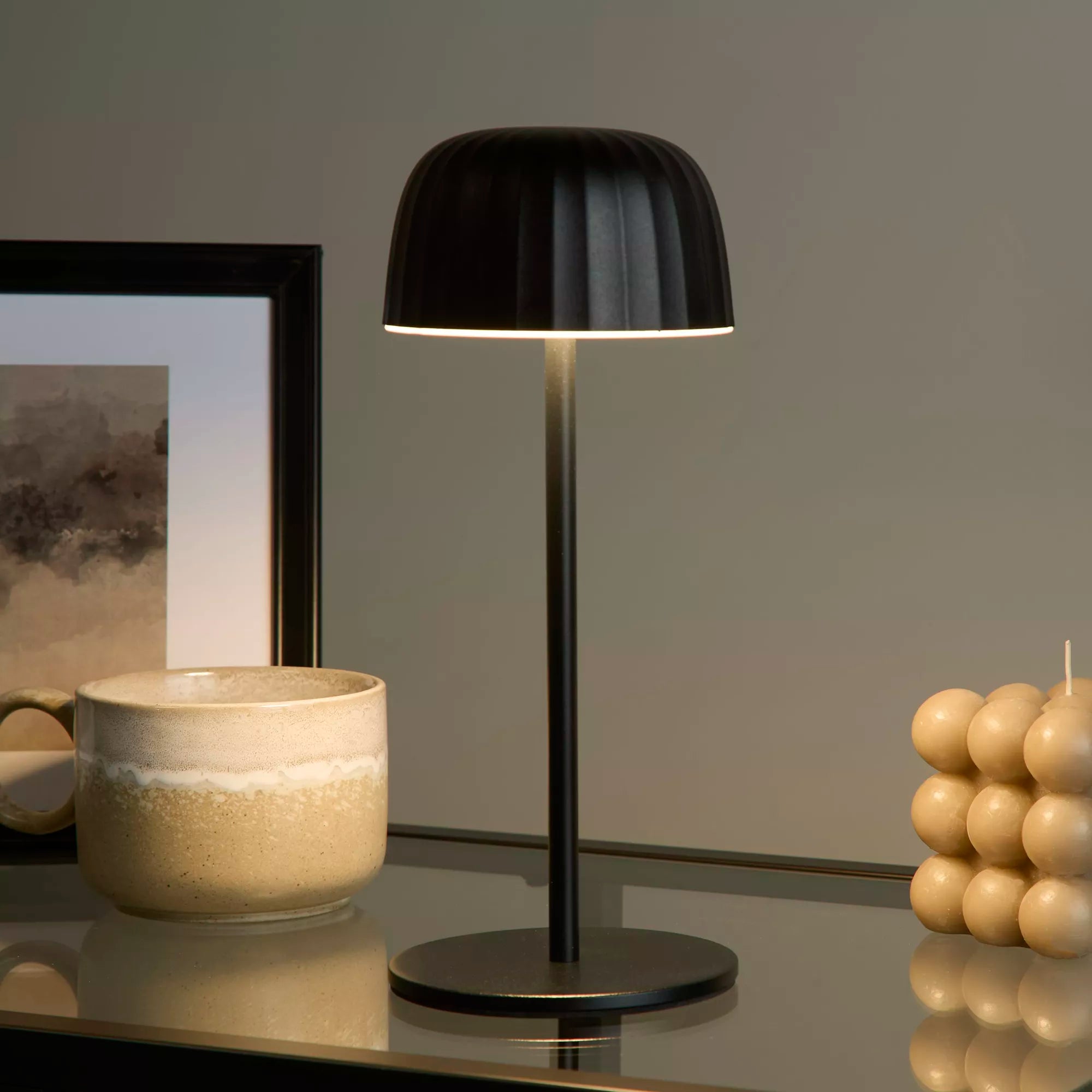 Black table lamp on a reflective surface with a neutral background