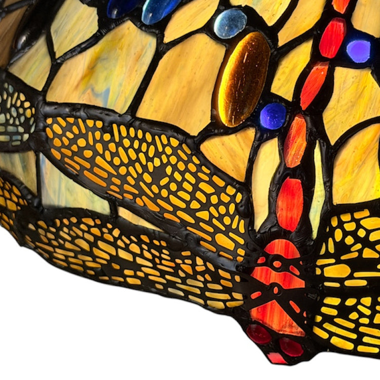 Close-up of a colorful stained glass lamp with a dragonfly design on a white background