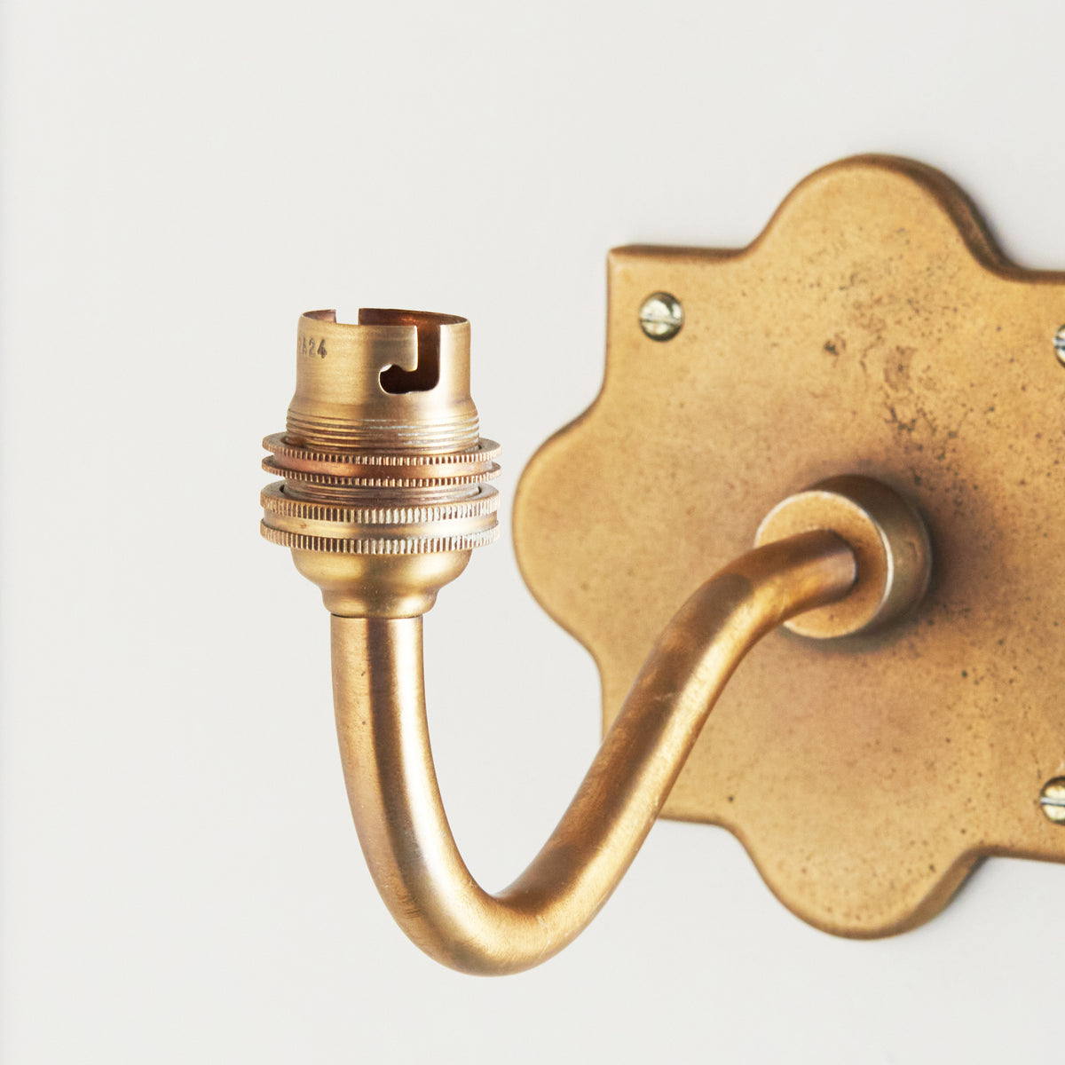 Close-up of the Anvil Curve wall light's threaded brass bulb holder and gently curving arm