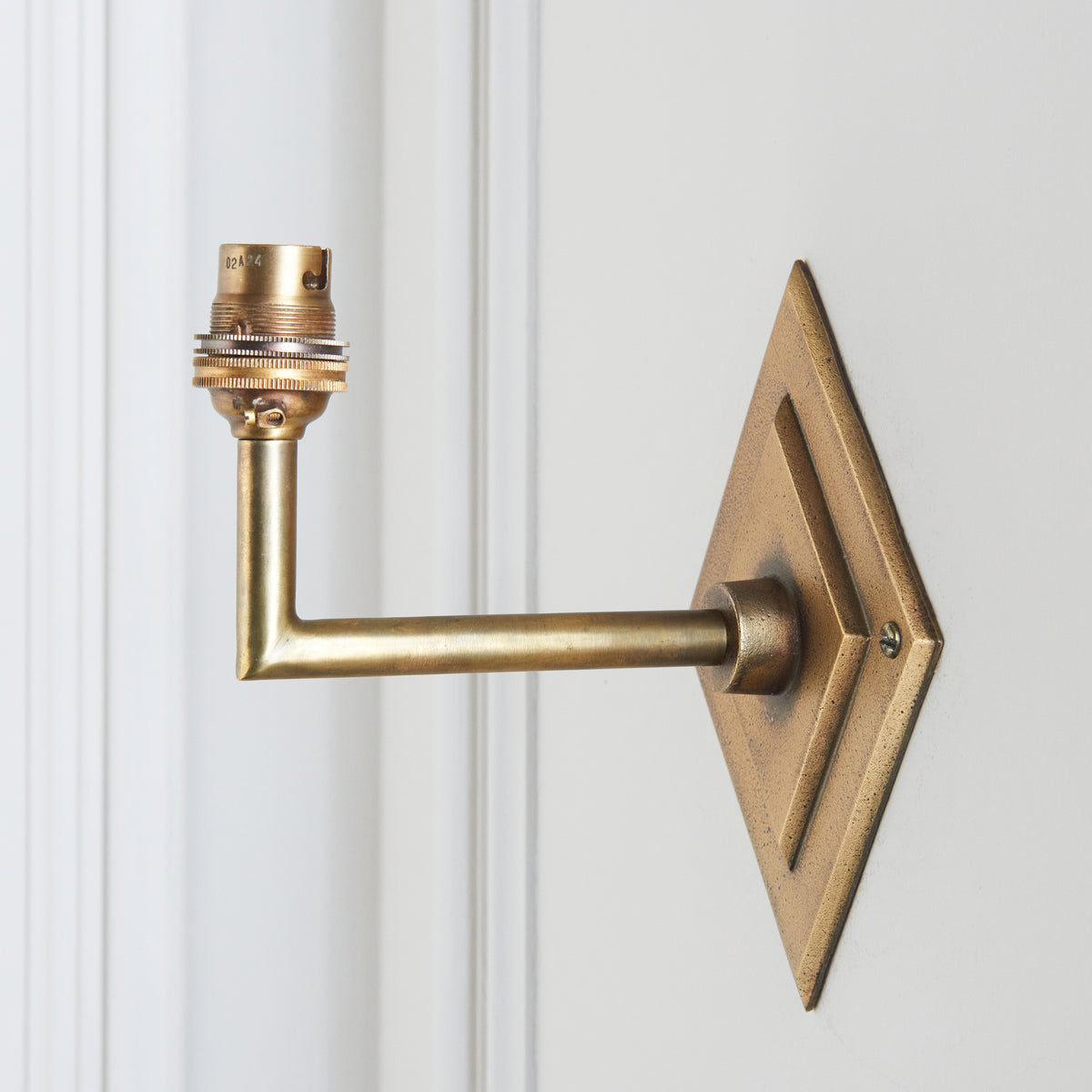Side view of the Diamond Angle wall light showing the diamond brass plate and right-angled arm on panelling