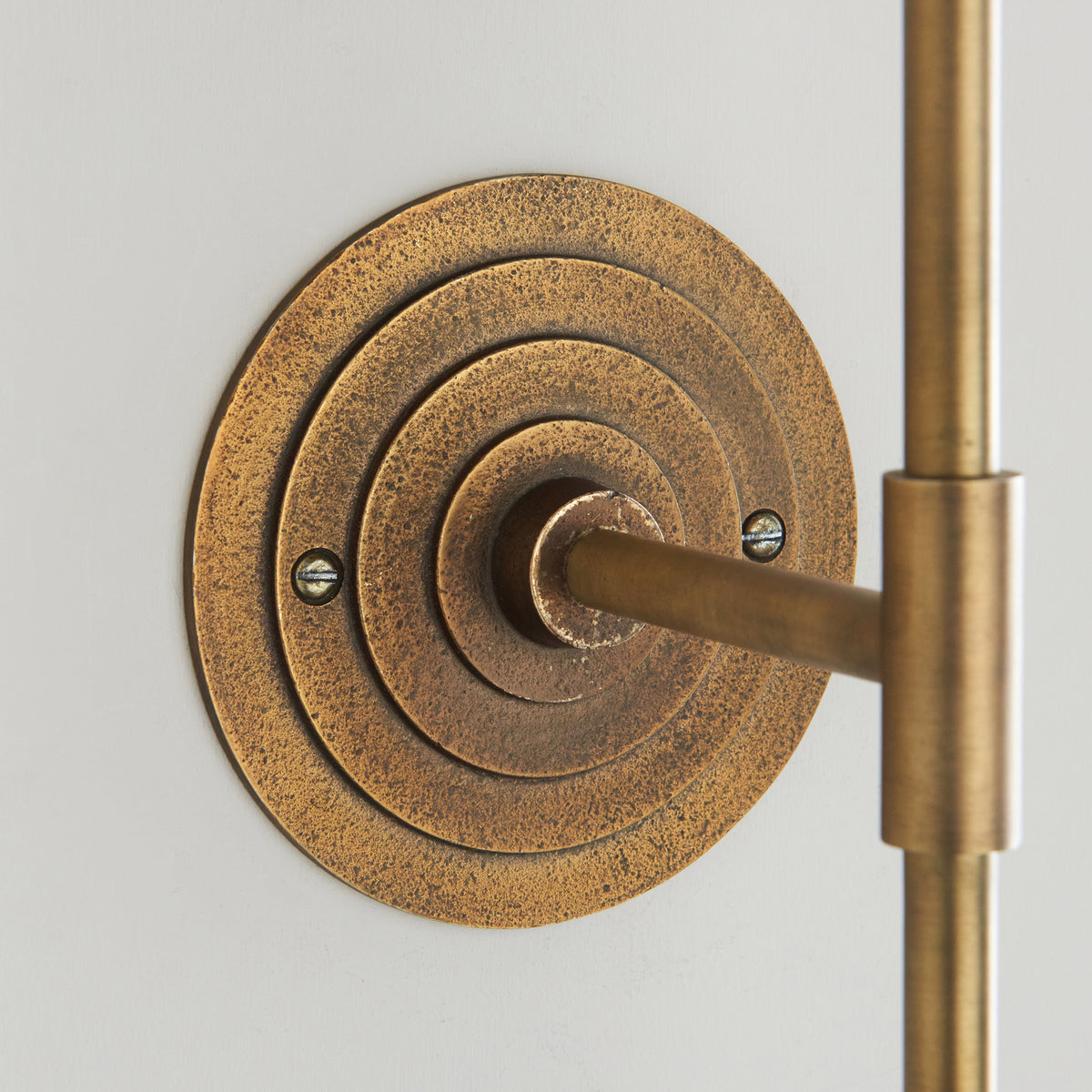 Close-up of the concentric ringed antique brass backplate of the Halo Tall wall light