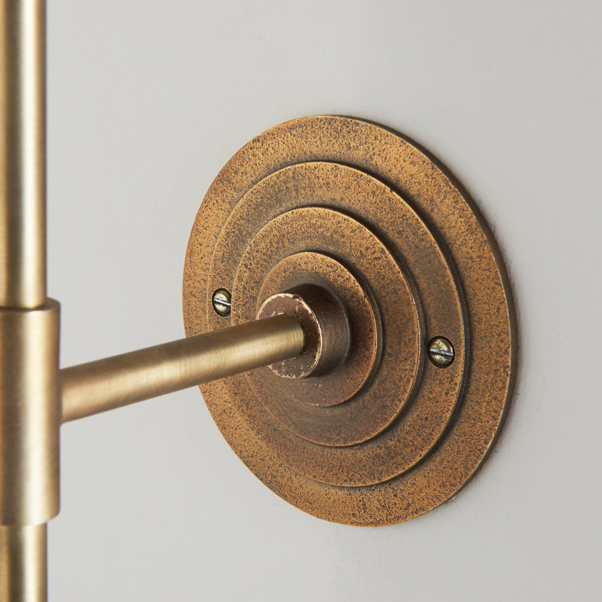 Detail of the aged brass halo backplate where the Halo Tall wall light's arm joins the wall