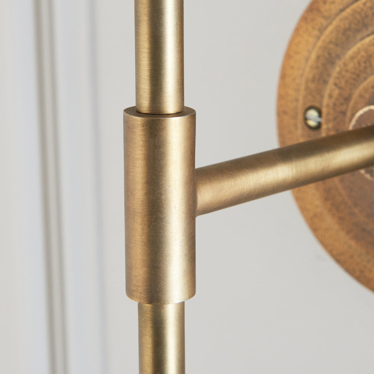 Close-up of the brushed brass T-joint linking stem and arm on the Halo Tall wall light