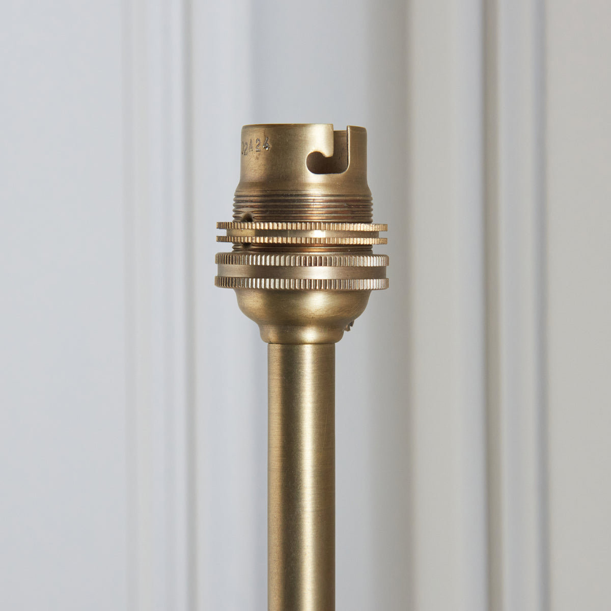 Close-up of the ribbed brass bayonet bulb holder at the top of the Halo Tall wall light stem