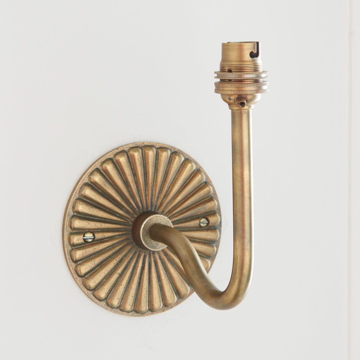 Side view of the Dahlia Swan wall light showing its fluted oval brass backplate and sweeping arm