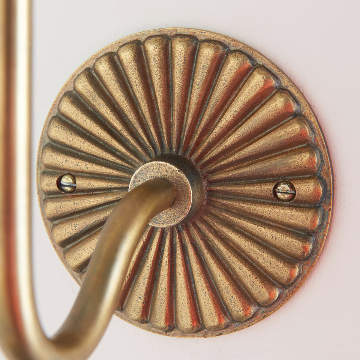 Close-up of the petal-fluted antique brass backplate of the Dahlia Swan wall light