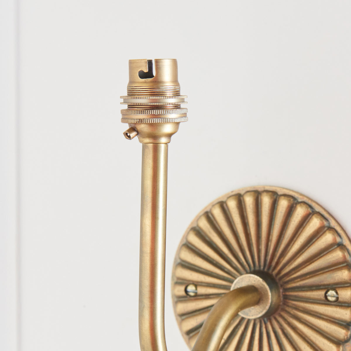 Close-up of the brass lampholder above the curved arm of the Dahlia Swan wall light
