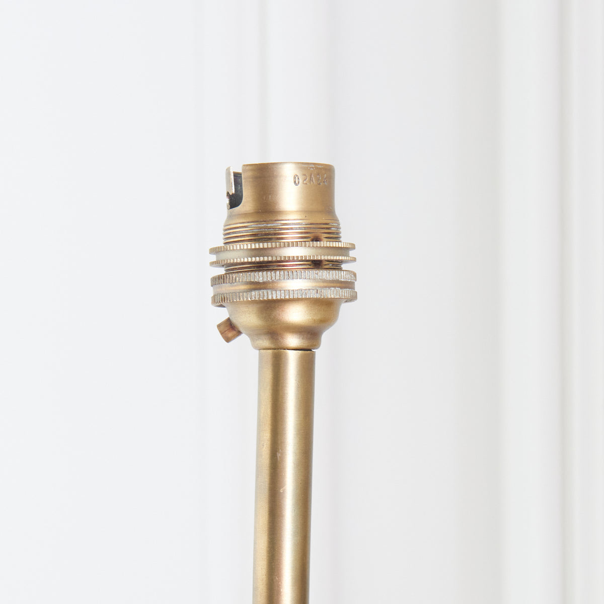 Tight crop of the ribbed brass bayonet bulb holder on the Dahlia Swan wall light stem