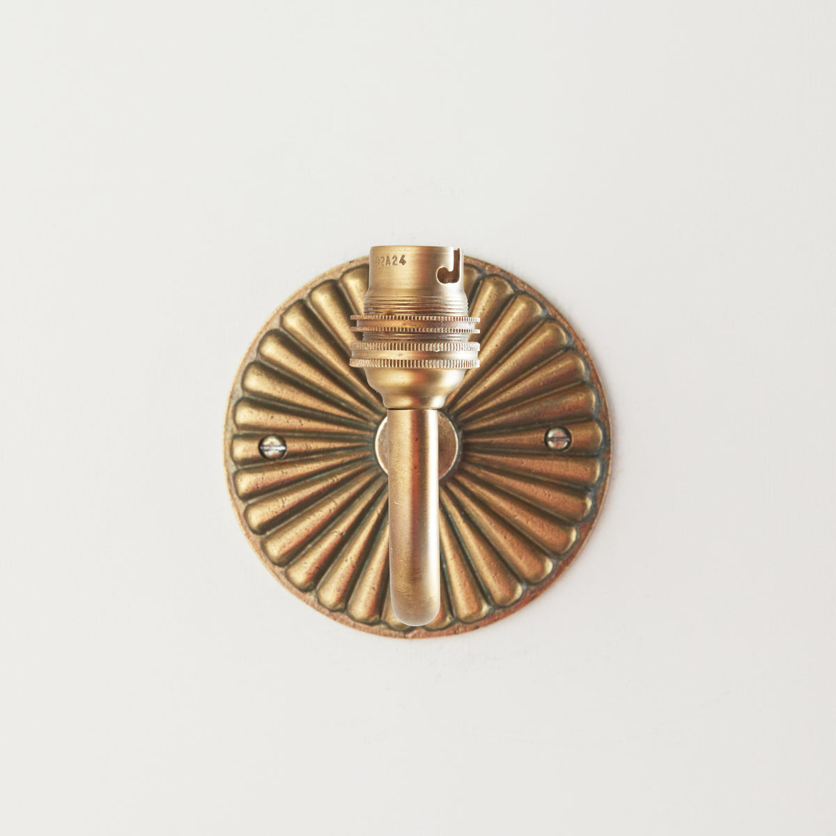 Head-on view of the Dahlia Curve wall light showing the fluted petal brass backplate and lampholder