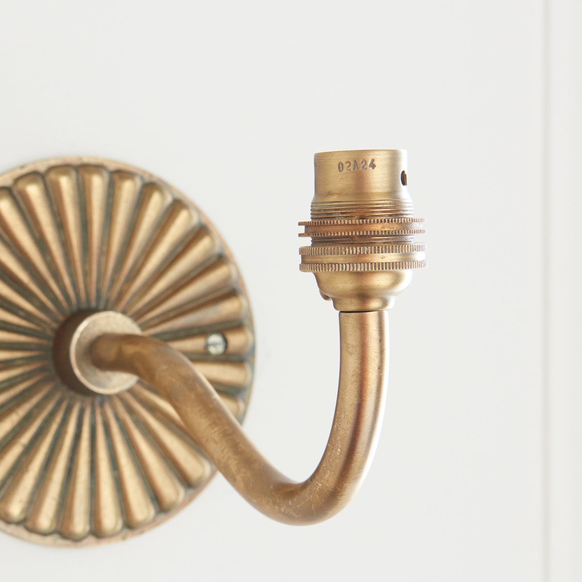 Close-up of the brass bulb holder on the curved arm of the Dahlia Curve wall light
