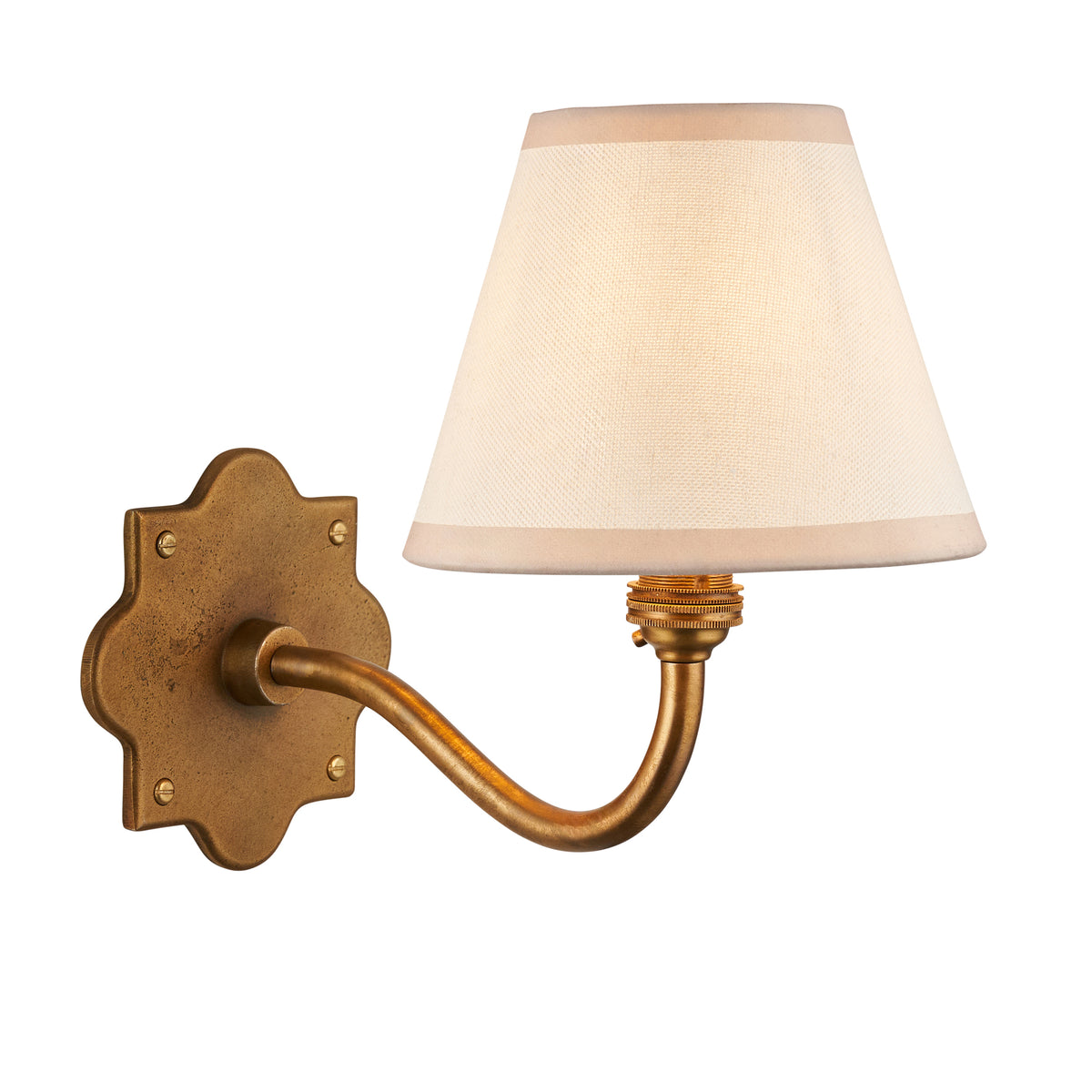 Anvil Curve antique brass wall light with a tapered ivory fabric shade on a scalloped backplate