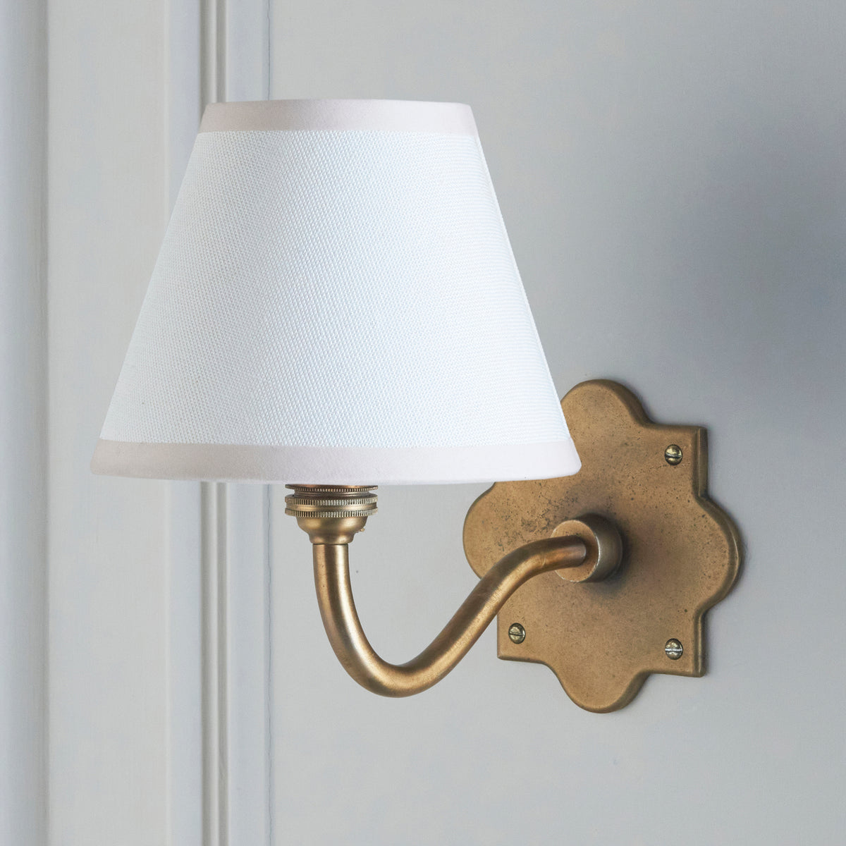 Anvil Curve wall light with crisp white tapered shade mounted on pale panelling