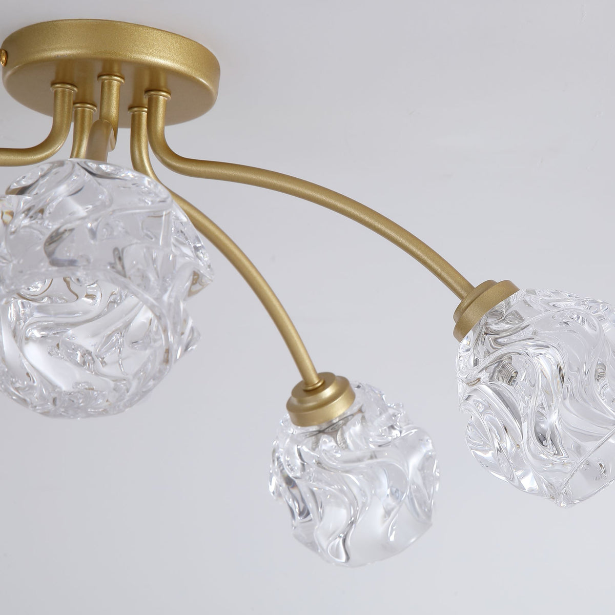 Detail of Astral textured clear glass globes on curved brushed gold arms
