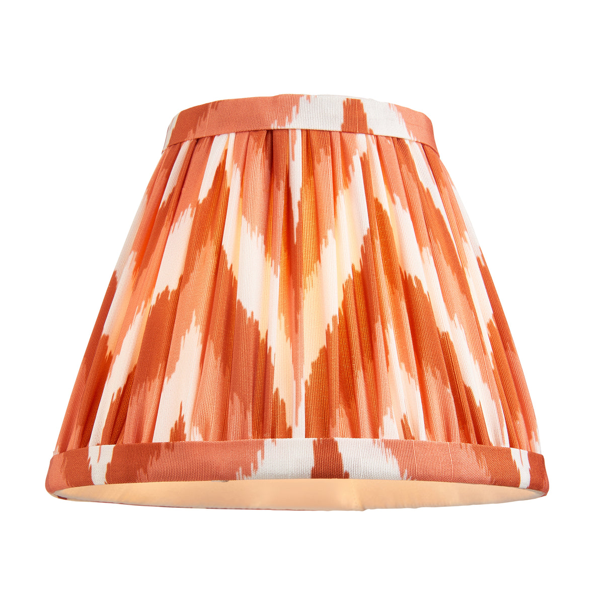 Orange zigzag ikat pleated tapered lampshade lit from inside, shown alone on white