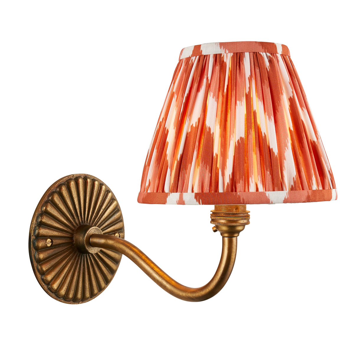 Dahlia Curve antique brass wall light with a pleated orange ikat zigzag shade on a fluted oval backplate